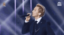 a man in a suit is singing into a microphone .
