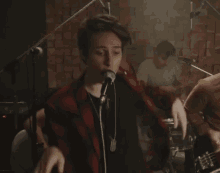 a man is singing into a microphone while playing drums