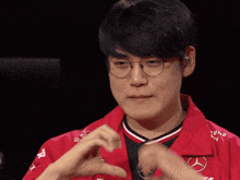 a man wearing glasses and a red shirt with a mercedes logo on it
