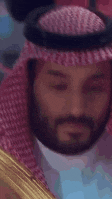 a close up of a man wearing a pink scarf and a yellow robe .