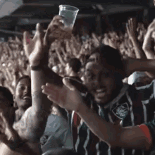 a man in a striped shirt holds a cup in his hand