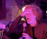 a man is singing into a microphone with a purple background