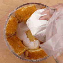 a person holding a bag of frosting over a cake