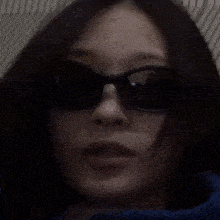 a woman wearing sunglasses is covering her mouth with her hands