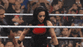 a woman is in a wrestling ring with a crowd behind her and a sign that says win