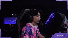 a man is sitting in a gaming chair with his arms in the air and the word replay is on the bottom right