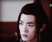 a close up of a man 's face with a ponytail on his head