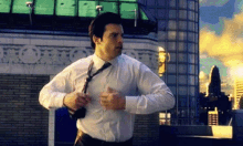 a man in a white shirt and tie is running across a city .