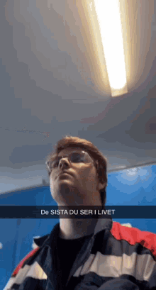 a man wearing glasses and a jacket with the words de sista du ser i livet written on the bottom