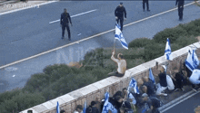 a man is sitting on a wall holding a flag with the number 12 in the corner