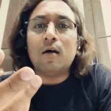 a man with long hair wearing glasses and headphones making a funny face