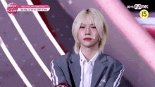 a girl with blonde hair and red lipstick is standing in front of a mnet banner