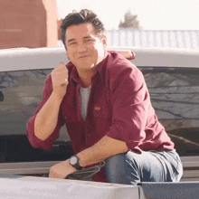 a man in a maroon shirt is sitting in the back of a truck