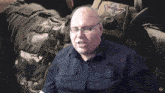 a bald man wearing glasses and a black shirt with a medical symbol on his sleeve