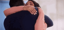 a man and a woman are hugging each other . the woman is wearing a pink sweater .