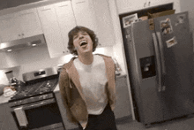 a young man is standing in a kitchen with his mouth open and laughing .