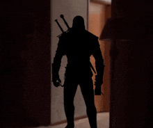 a silhouette of a man with a sword on his back standing in a dark hallway