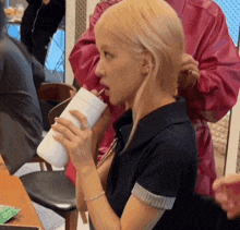 a woman with blonde hair drinking from a white cup