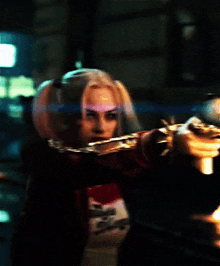 a woman in a harley quinn costume holds a gun