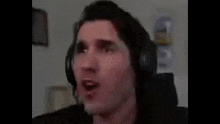 a man wearing headphones is making a funny face while sitting in a chair .