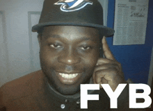 a man wearing a blue jays hat talks on a phone