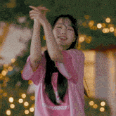 a girl wearing a pink shirt that says " aspirin " is clapping her hands
