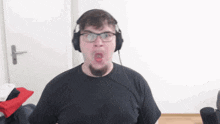 a man wearing headphones and a black shirt making a funny face