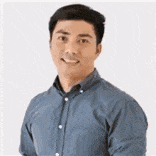 a man in a blue shirt is smiling and looking at the camera