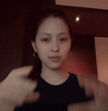 a woman wearing a black tank top and earrings is making a funny face
