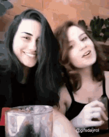 a couple of women sitting next to each other with a glass of water in front of them
