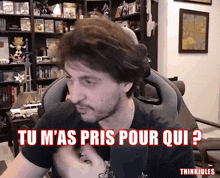 a man sitting in a chair with the words " tu m'as pris pour qui " written in red