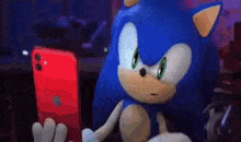 sonic the hedgehog is sitting in a chair looking at a red cell phone .