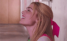 a woman with a pink bow in her hair is smiling .