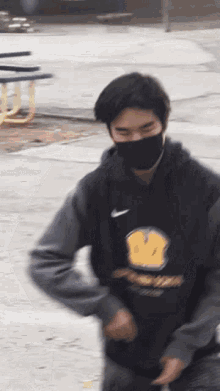 a man wearing a black nike hoodie with a yellow smiley face