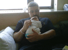 a man is holding a baby in his arms while sitting on a couch