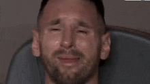 a man with a beard is crying with tears running down his face while sitting in a chair .