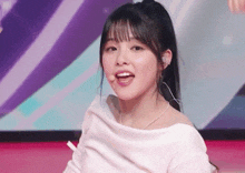 a close up of a woman wearing a white off the shoulder top and earrings .