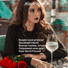 a woman is sitting at a table with a glass of wine and a red rose