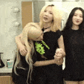 a blonde girl wearing a black shirt that says witcher is hugging another blonde girl