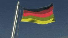 a german flag flies in the wind against a blue sky