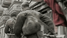 a black and white photo of soldiers walking in front of a building that says ' a ' on it