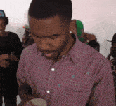 a man in a pink shirt is standing in a crowd of people .