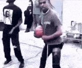 two men are standing next to each other in a room . one of the men is holding a basketball in his hand .