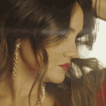 a close up of a woman 's face wearing earrings and a nose ring
