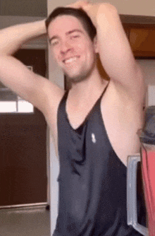 a man wearing a black tank top is smiling and holding his head
