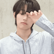 a person wearing a grey hoodie covering their face