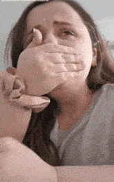 a woman is covering her mouth with her hand and crying
