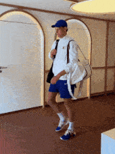 a man in a white jacket and blue shorts is carrying a nike bag