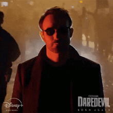 a man wearing sunglasses stands in front of a daredevil born again poster