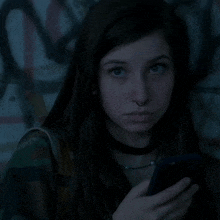 a girl with a nose ring is looking at her cell phone